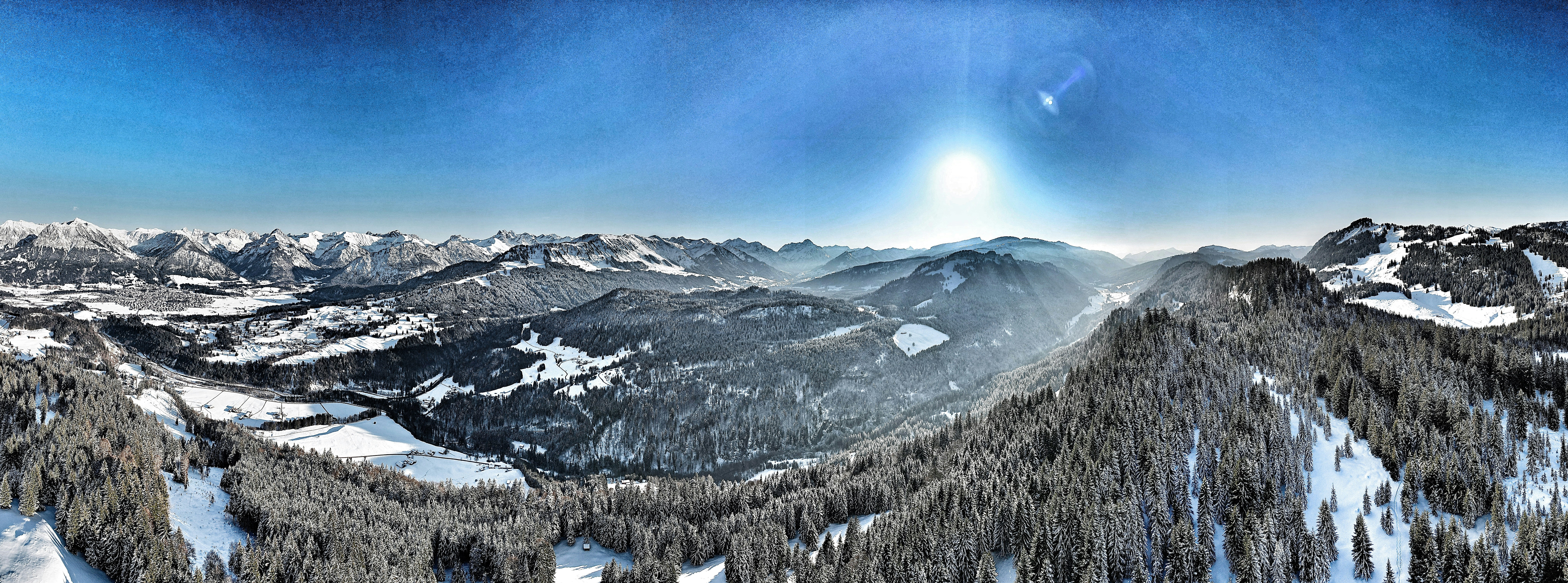 Blick auf eine schneebedeckte Bergkette mit einem hellen Heiligenschein am Himmel
