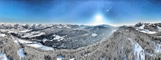 A panoramic view of snow-covered alpine slopes under a clear blue sky.
