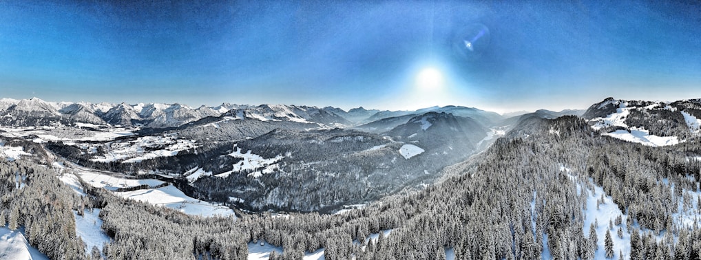 A panoramic view of snow-covered alpine slopes under a clear blue sky.
