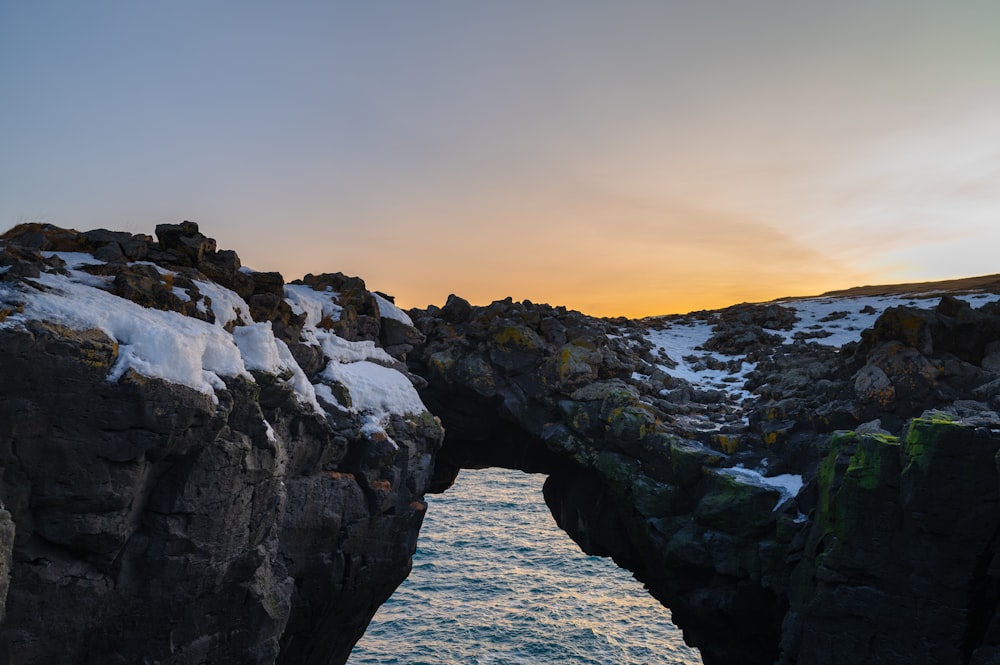 the sun is setting over the water and rocks