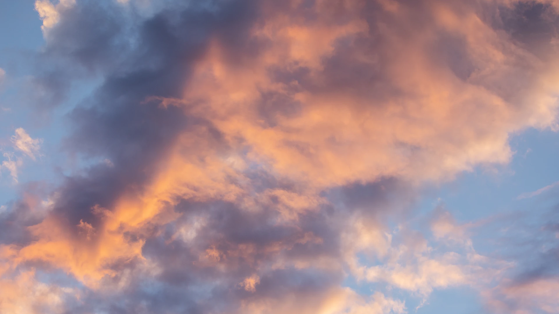 a plane flying through a cloudy sky at sunset