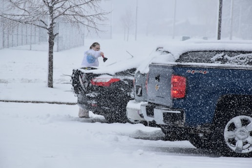 Woman clearing snow off a car