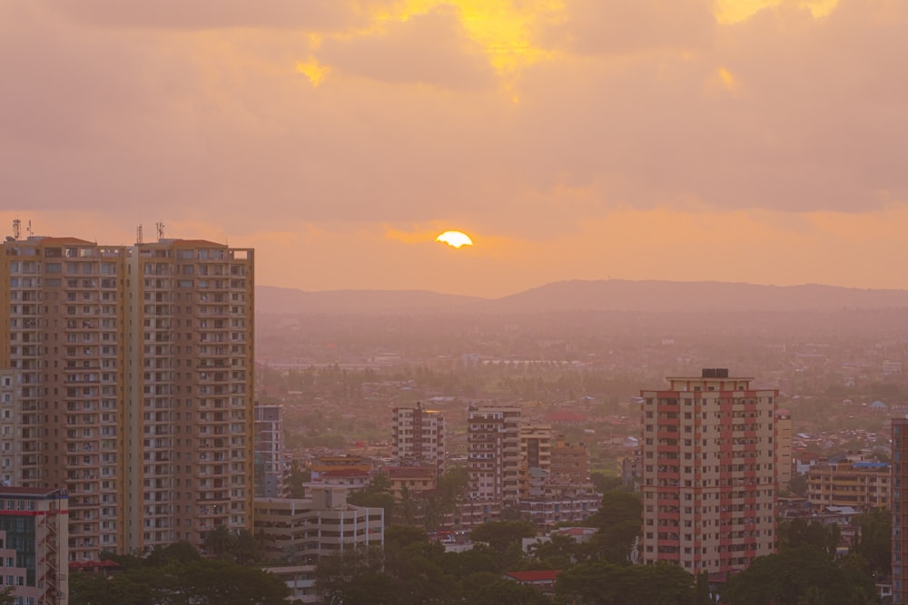 the sun is setting over a city with tall buildings