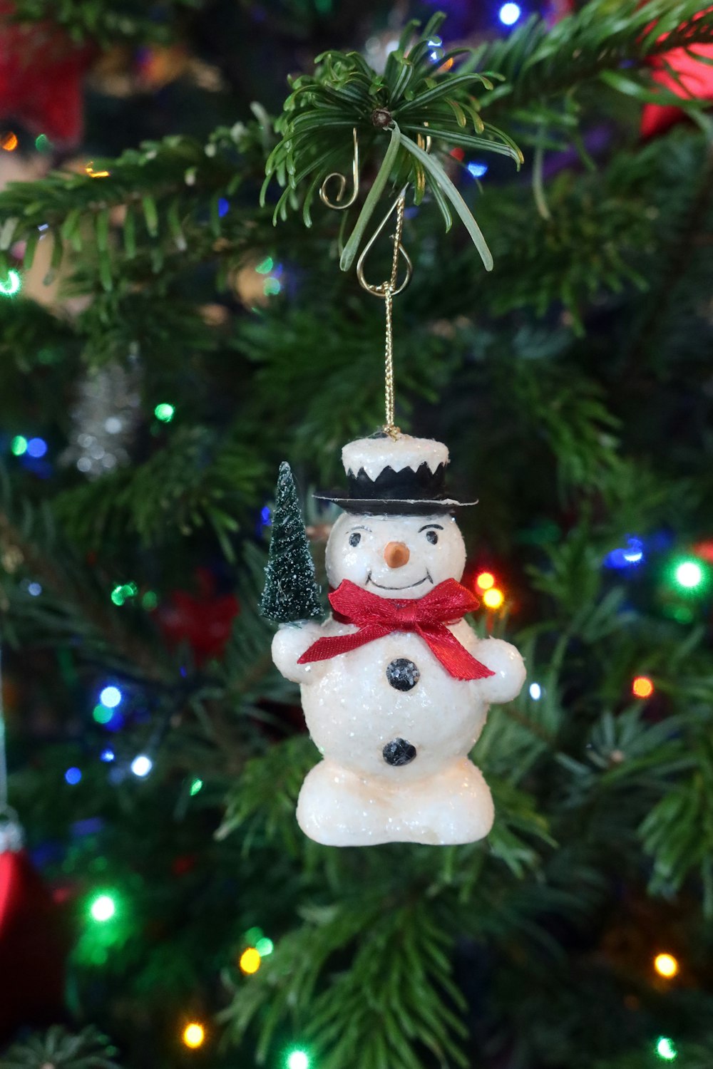 a snowman ornament hanging from a christmas tree