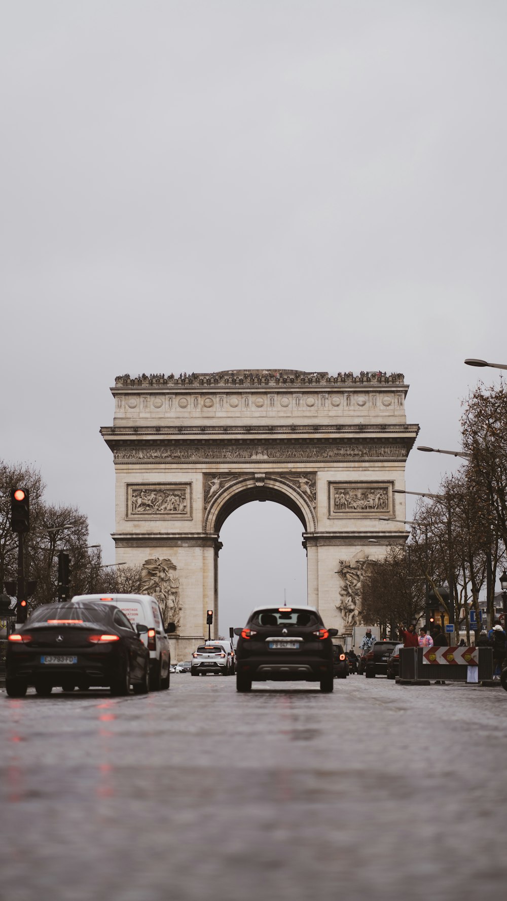 cars driving down the street in front of the arc de trioe