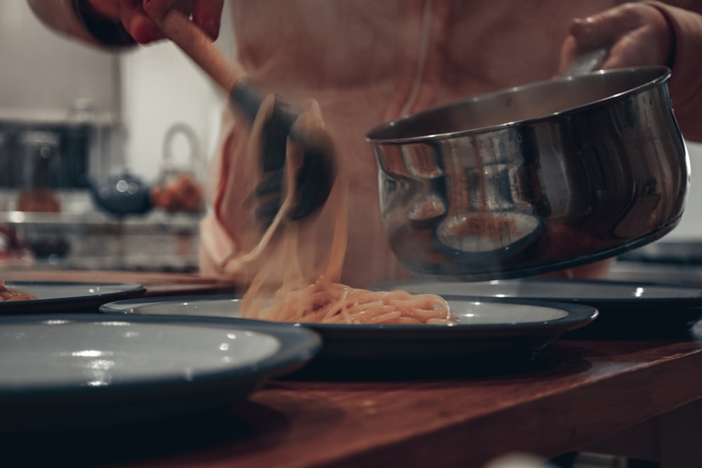 a person cooking pasta in a pot on a stove