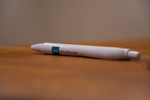 A white pen with 'BMI Healthcare' printed on it rests on a wooden surface. The background is blurred, highlighting the pen as the focal point.