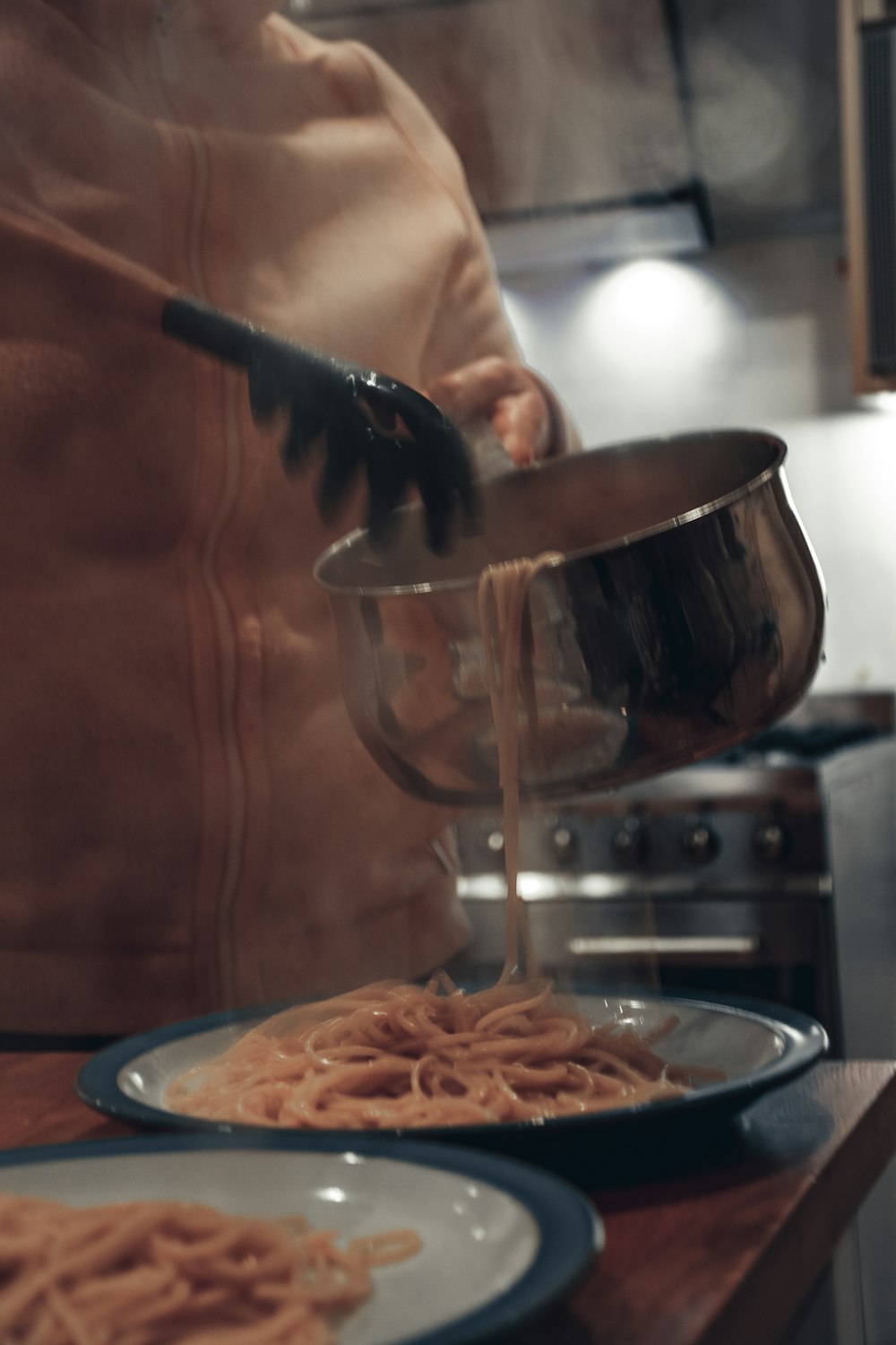 a person pouring sauce on a plate of pasta