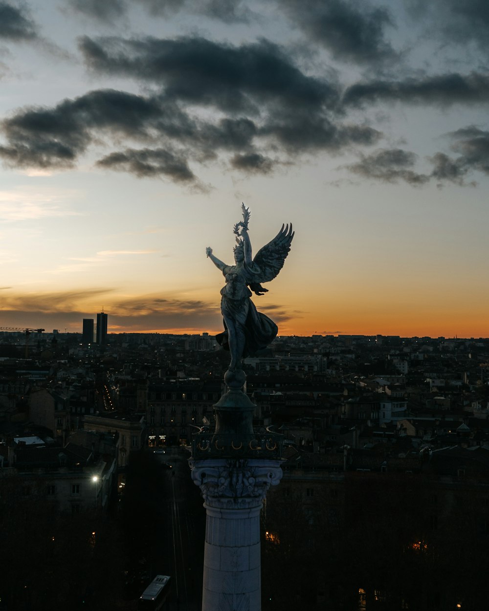 a statue on top of a building with a sunset in the background