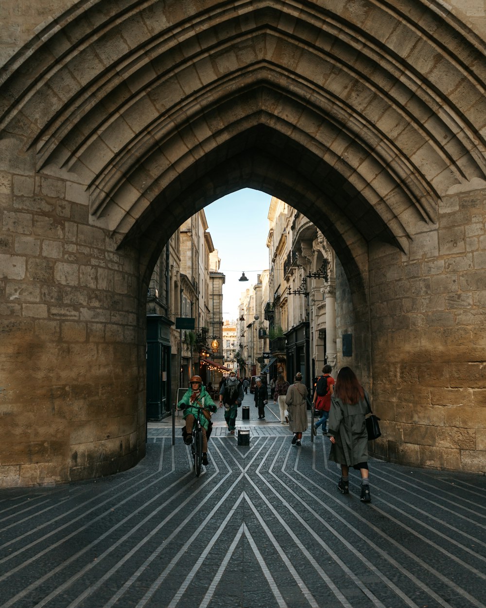 a group of people walking down a street under a bridge