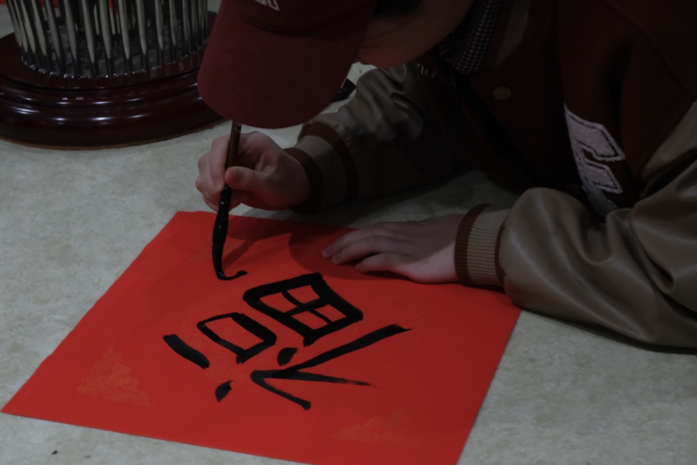 a person writing on a piece of red paper