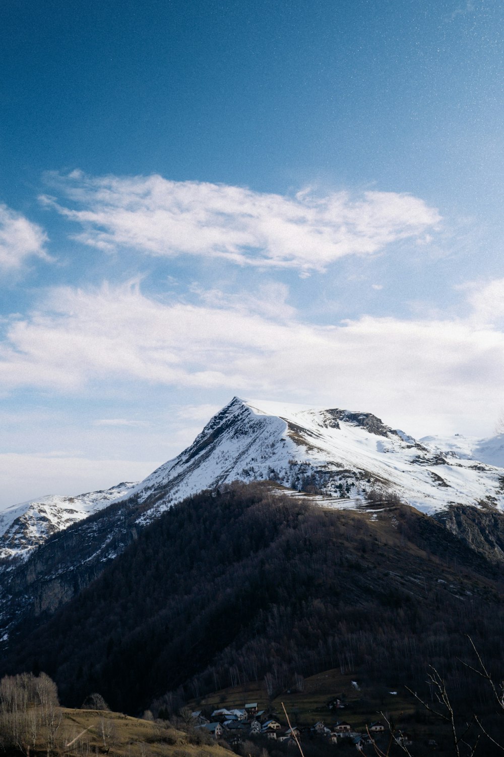 a snow covered mountain with a few clouds in the sky