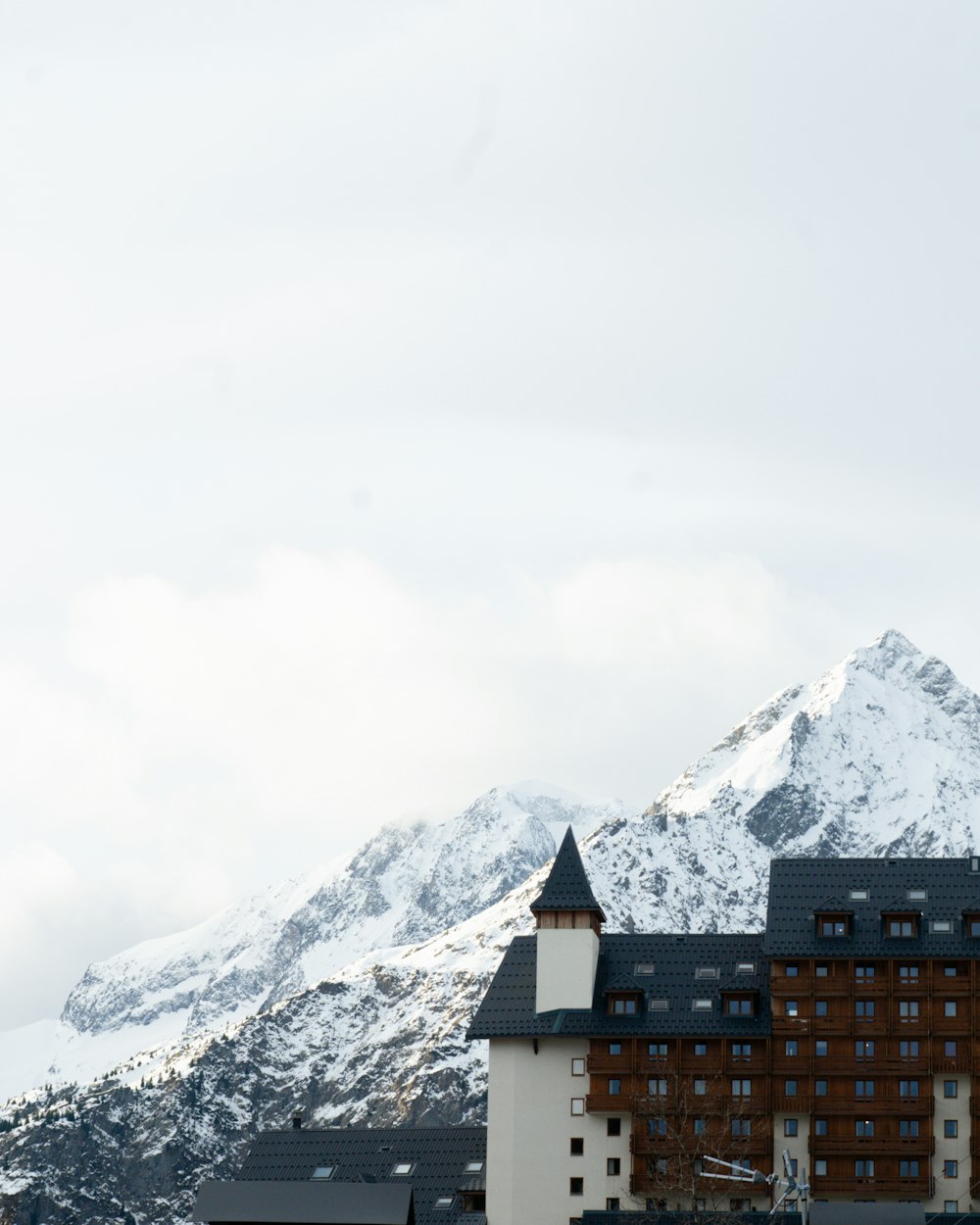 a large building with a clock tower in front of a snowy mountain