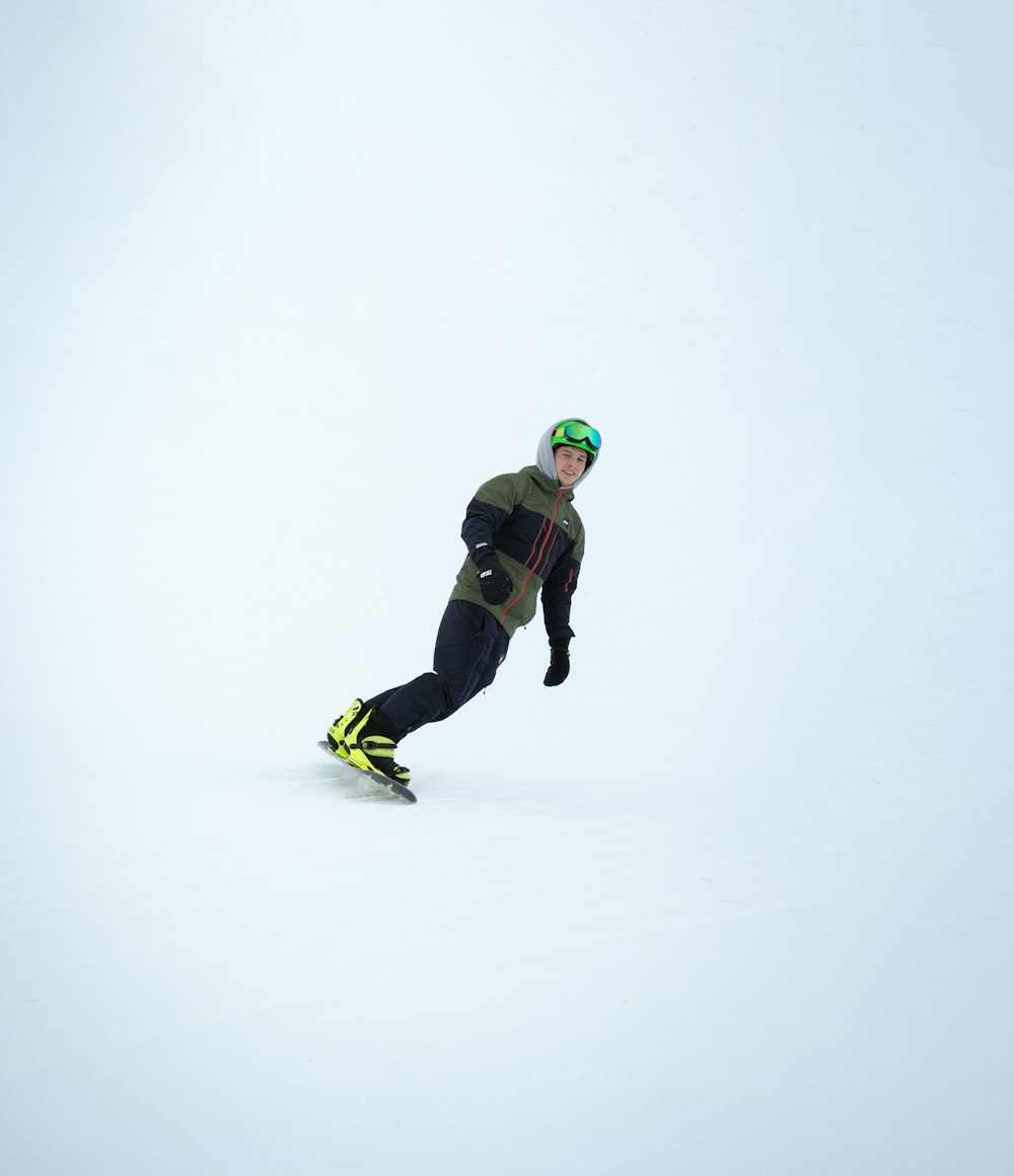 a man riding a snowboard down a snow covered slope