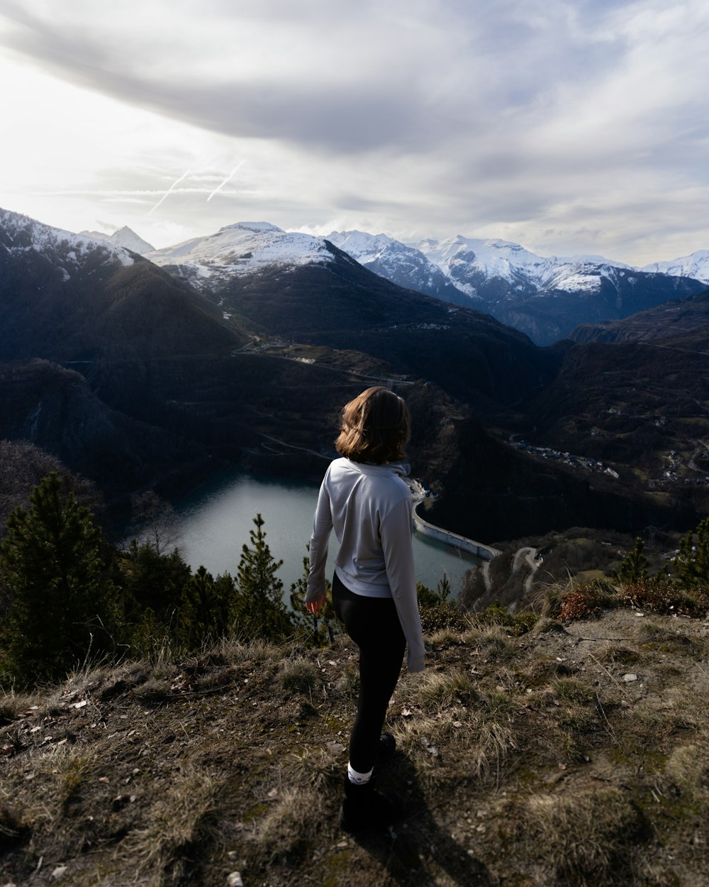 a woman standing on top of a lush green hillside