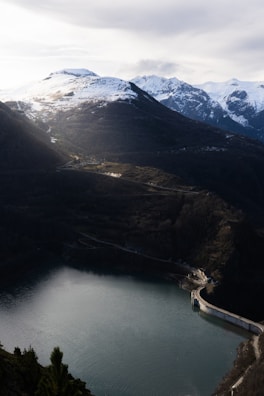 Sunset view of a dam with water flowing and mountains in the background.