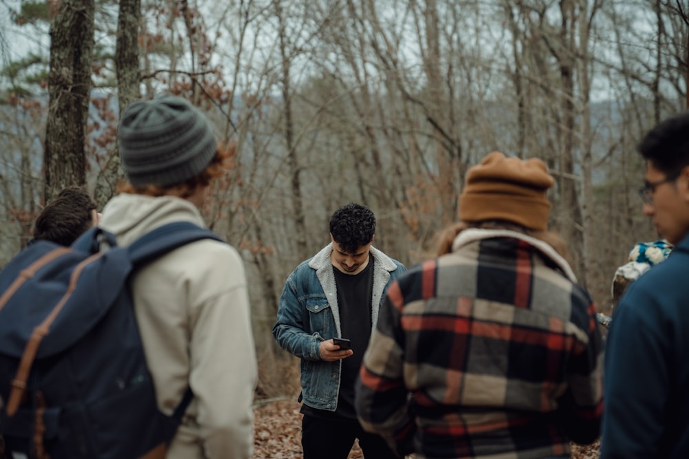 a group of people standing around each other in the woods