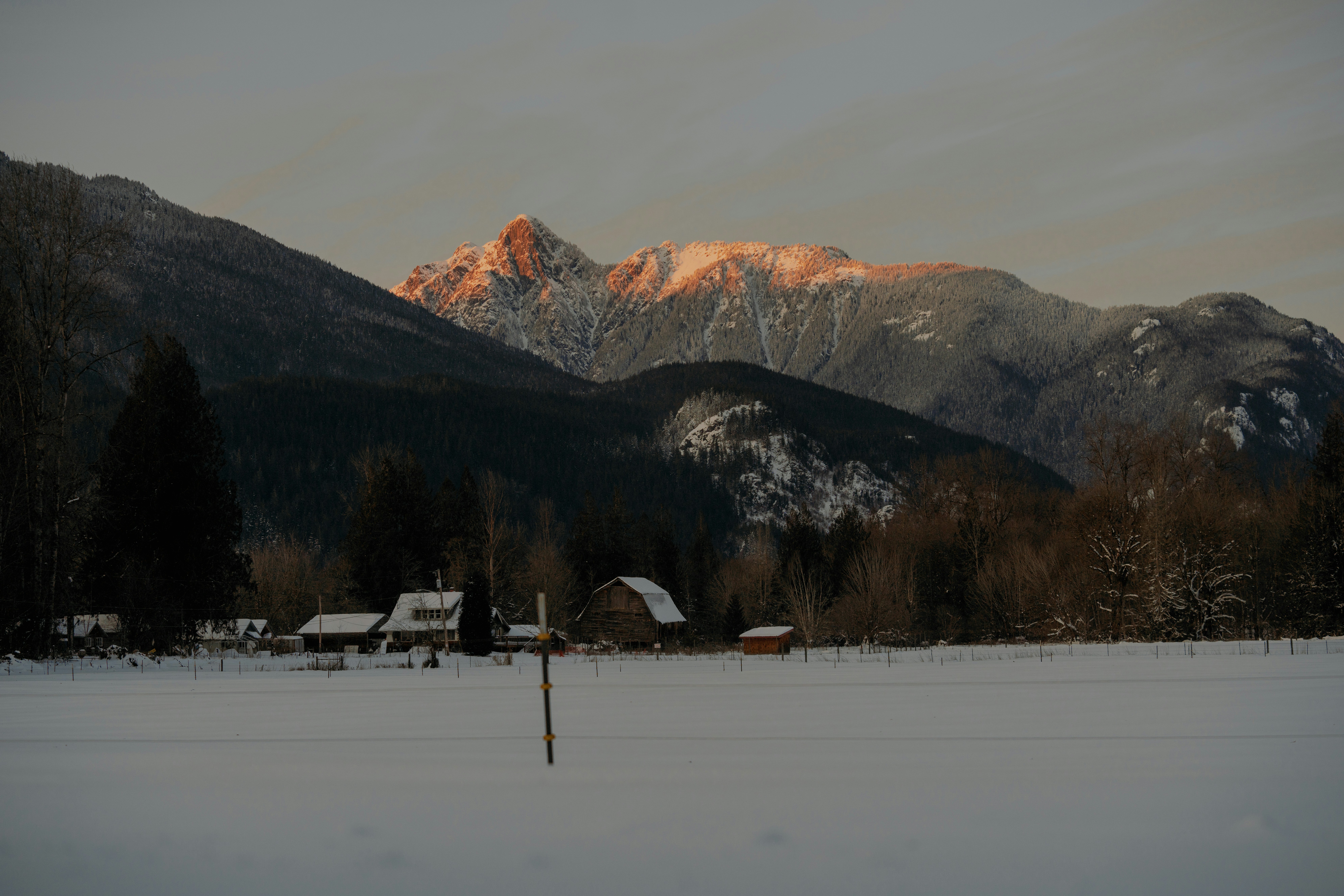 a snow covered field with mountains in the background