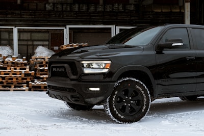 a black ram truck is parked in the snow