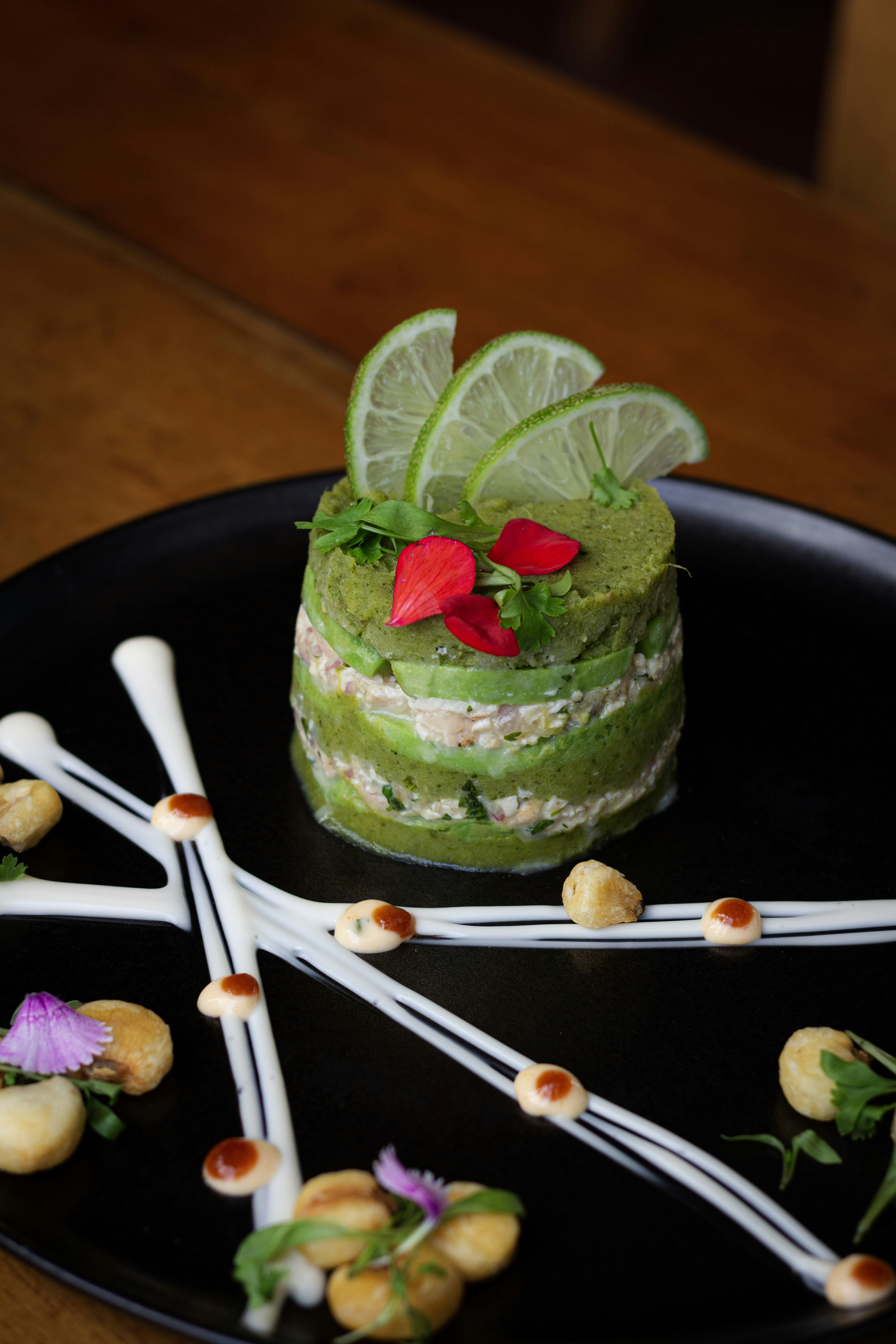 a black plate topped with a cake covered in green frosting