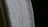 A close-up view of a white textured fabric with intricate woven patterns, displayed against a dark background. The fabric edges appear detailed and the weave texture is clearly visible, emphasizing its tactile quality.