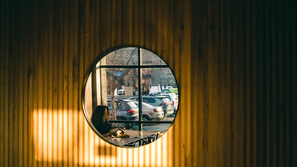 a person sitting in front of a round mirror