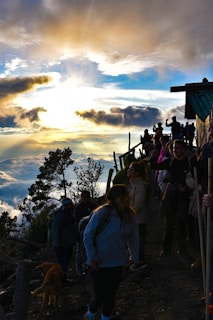 A group of friends enjoying a sunset view from a mountain peak, surrounded by snow-covered slopes.