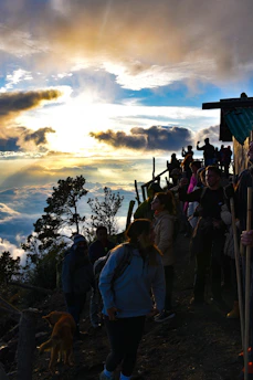 Group of friends trekking on a mountain trail during sunrise, smiling and enjoying the moment.