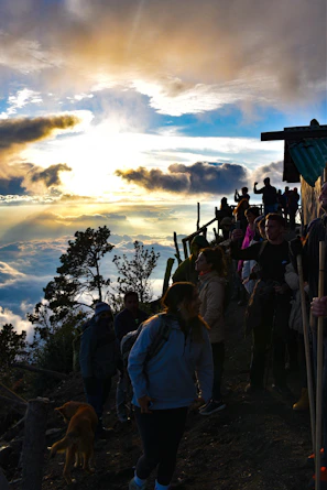 A group of friends smiling atop a scenic Himalayan mountain trail at sunrise.