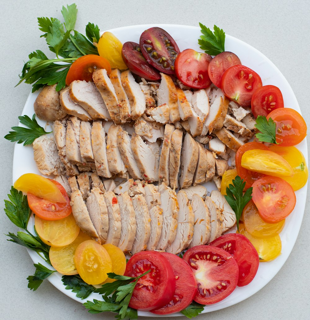 a white plate topped with sliced chicken and tomatoes