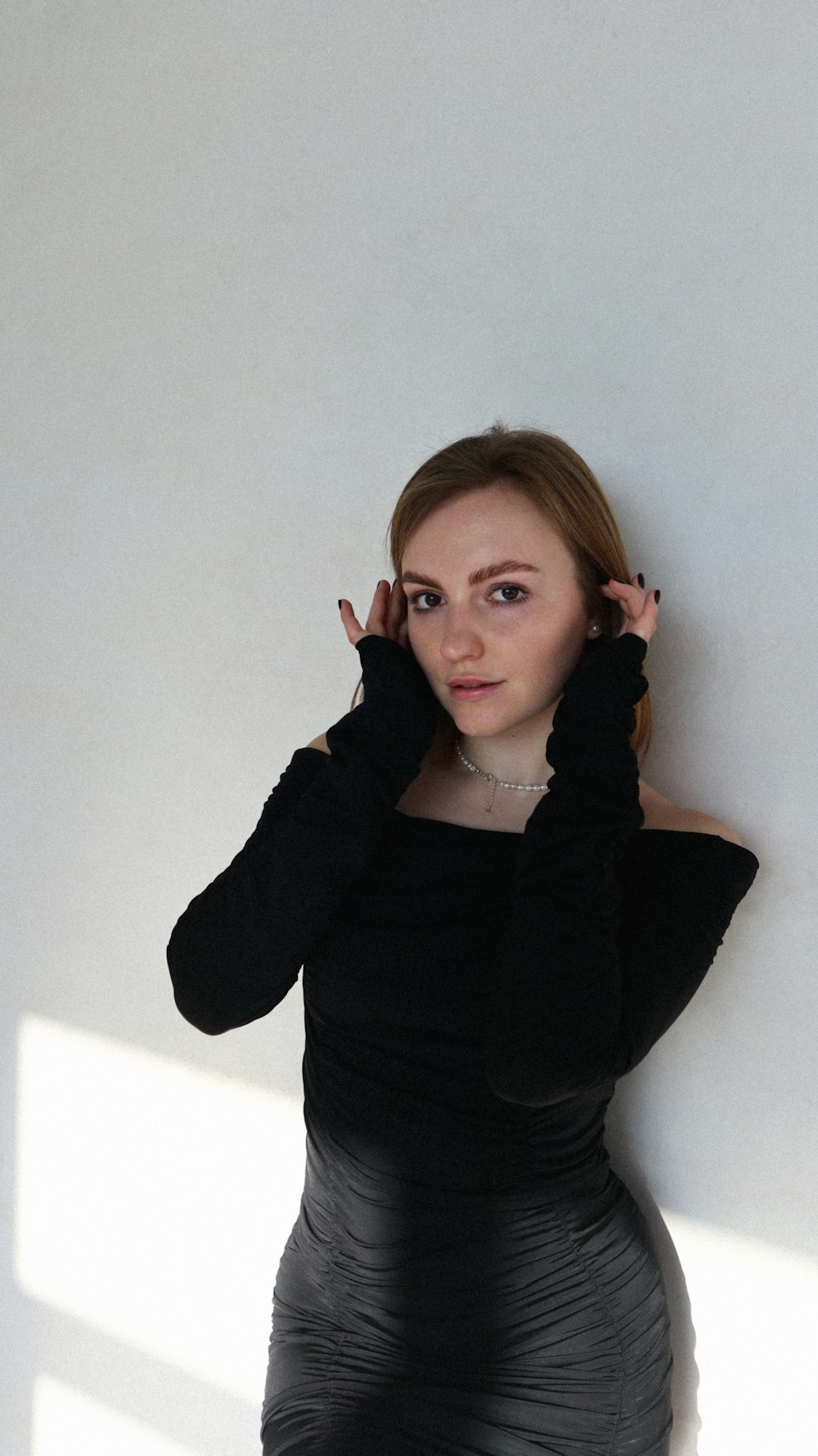 a woman in a black dress leaning against a wall