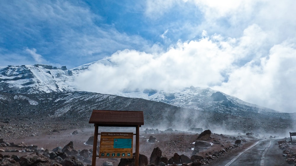 a sign in the middle of a road with a mountain in the background