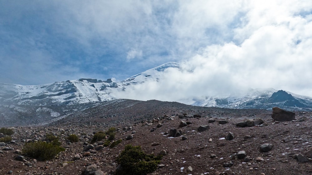 a mountain covered in snow and rocks under a cloudy sky