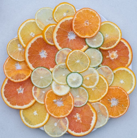 A cluster of citrus fruits—lemons and oranges—arranged artfully on a linen cloth with green leaves.