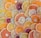A vibrant assortment of sliced citrus fruits, including oranges, lemons, limes, and grapefruits, arranged in an overlapping pattern. The slices display a variety of colors from deep red to bright yellow and green, showcasing the diverse textures and juices of the fruits.