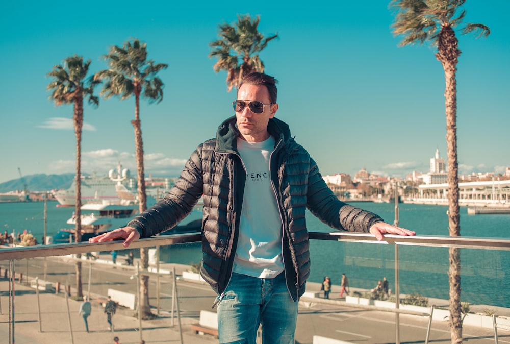 a man standing on a railing near a body of water