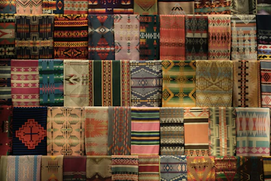 A collection of handwoven sarees with traditional patterns laid out on a wooden table.