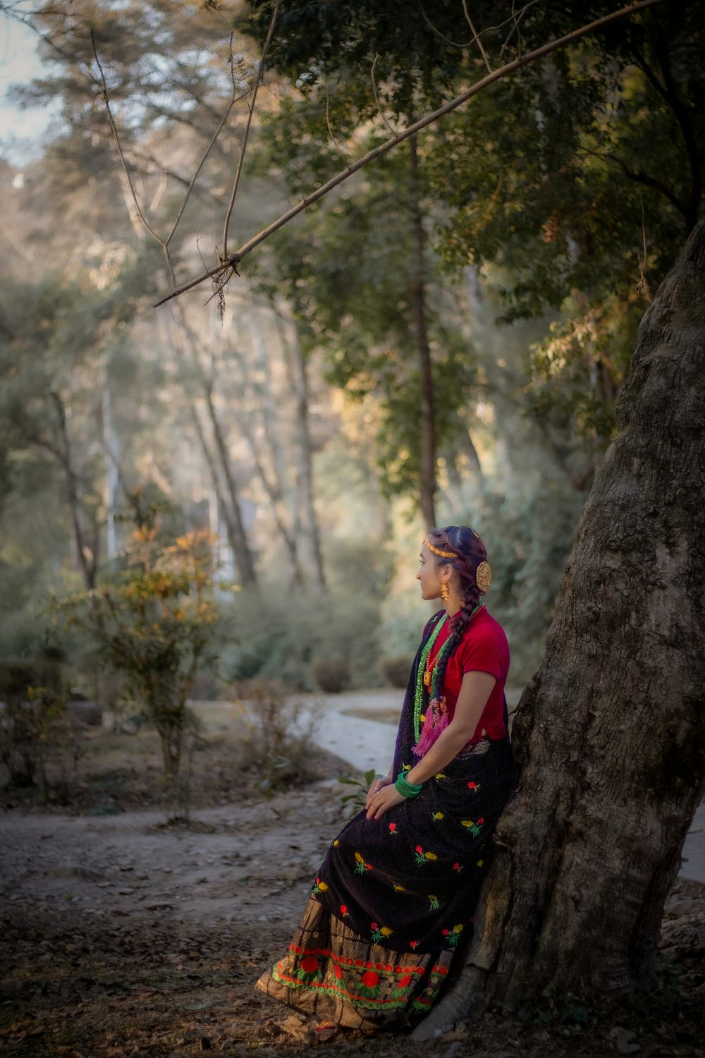 a woman sitting on a tree in a forest