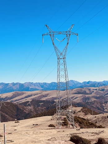 Power line towers stretching across a mountainous landscape under clear sky
