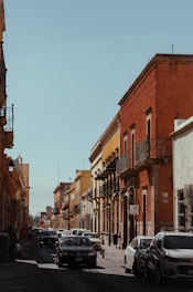 a city street lined with parked cars and tall buildings
