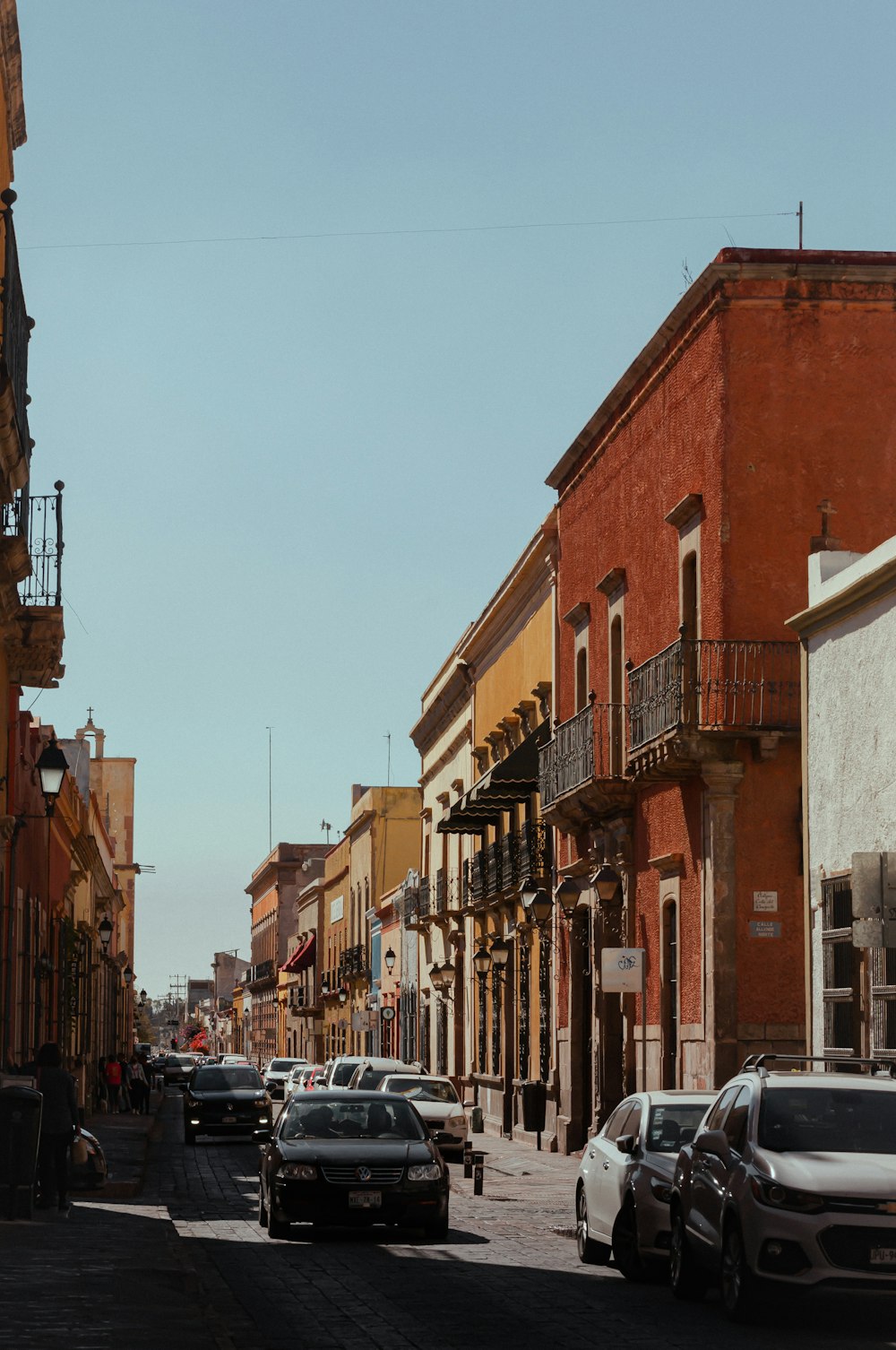 a city street lined with parked cars and tall buildings