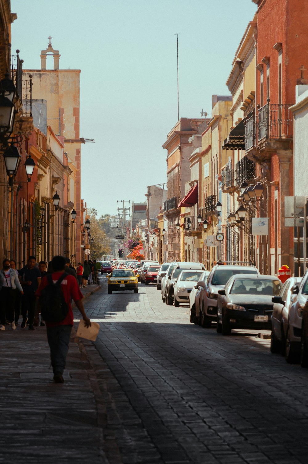 a man walking down a street next to parked cars