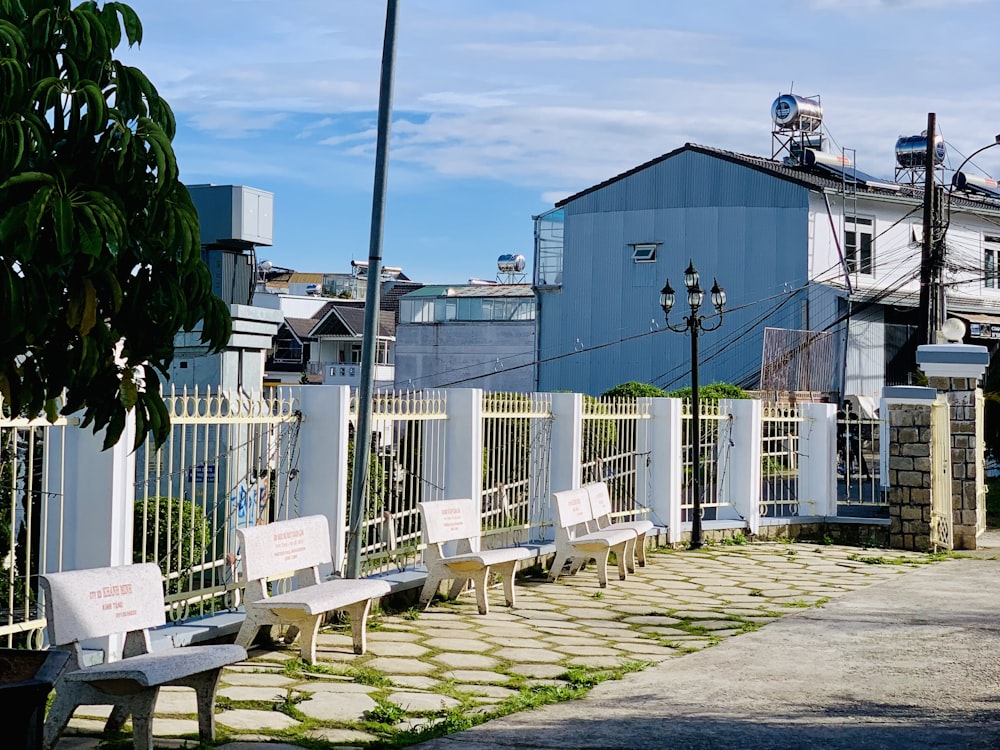 a row of benches sitting next to a white fence