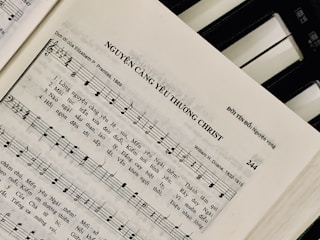 Sheet music featuring a hymn titled 'NGUYỆN CÀNG YÊU THƯƠNG CHRIST' with lyrics in Vietnamese. The page includes music notes, staff, and lyrics, suggesting a religious song. On the right side, a piano keyboard is partially visible.