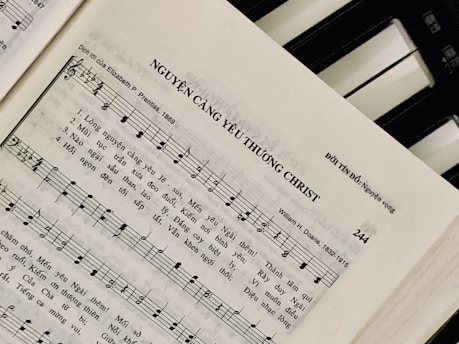 Sheet music featuring a hymn titled 'NGUYỆN CÀNG YÊU THƯƠNG CHRIST' with lyrics in Vietnamese. The page includes music notes, staff, and lyrics, suggesting a religious song. On the right side, a piano keyboard is partially visible.
