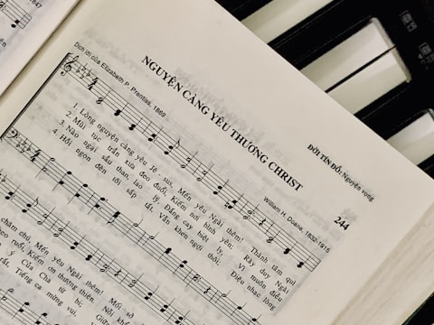 Sheet music featuring a hymn titled 'NGUYỆN CÀNG YÊU THƯƠNG CHRIST' with lyrics in Vietnamese. The page includes music notes, staff, and lyrics, suggesting a religious song. On the right side, a piano keyboard is partially visible.
