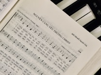 Sheet music featuring a hymn titled 'NGUYỆN CÀNG YÊU THƯƠNG CHRIST' with lyrics in Vietnamese. The page includes music notes, staff, and lyrics, suggesting a religious song. On the right side, a piano keyboard is partially visible.