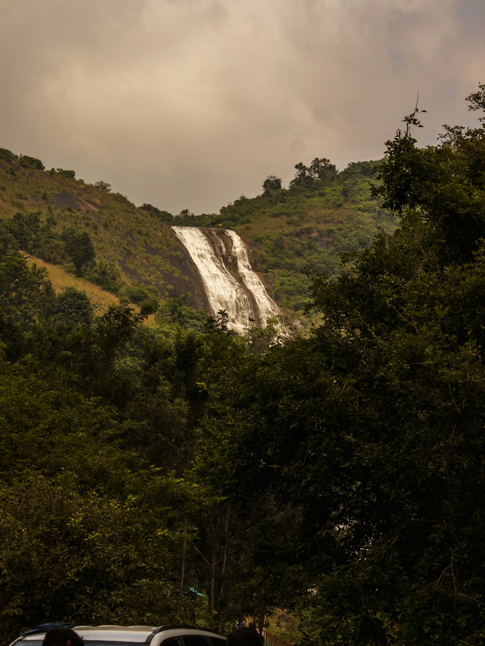 a car driving down a road next to a waterfall