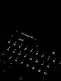 A dark image with a smartphone keyboard visible, displaying a message with the text 'Be happy 😊'. The keyboard is illuminated, showing a QWERTY layout.