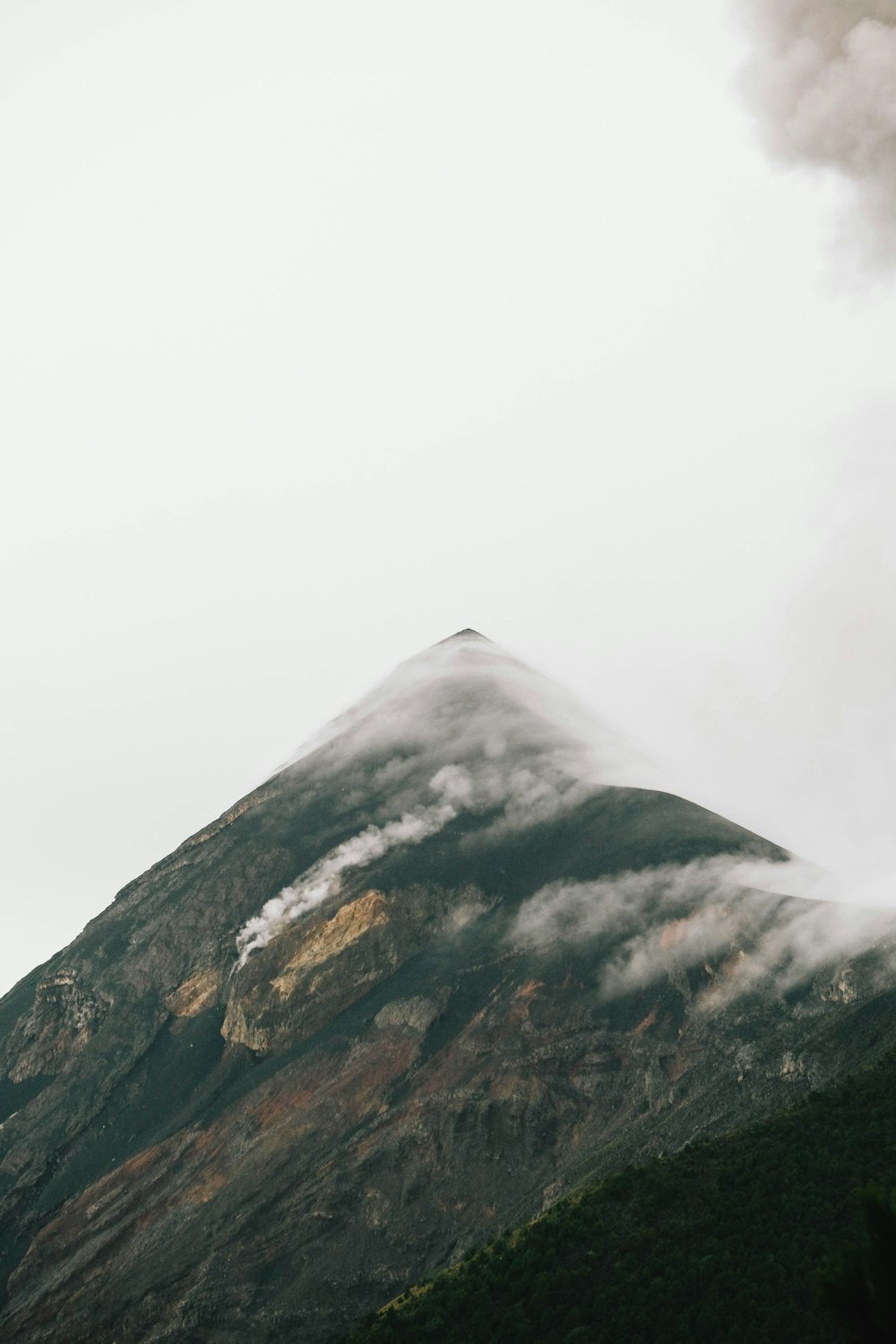 a very tall mountain covered in clouds and smoke